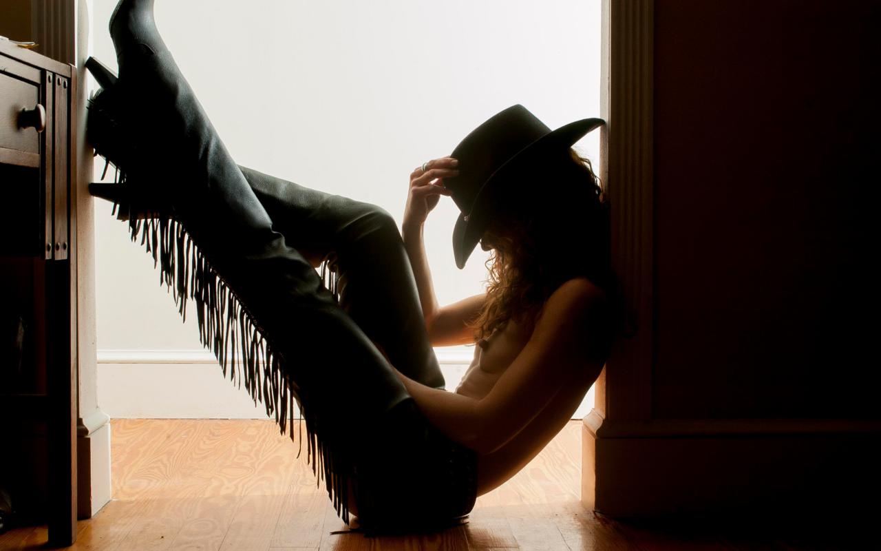 young, brunette, russian, model, slim, sexy babe, curly hair, posing, sitting, topless, tits, nipples, black, leather, chaps, boots, hat, erotic art, the variations of light and shade, cowgirl, cinematic
