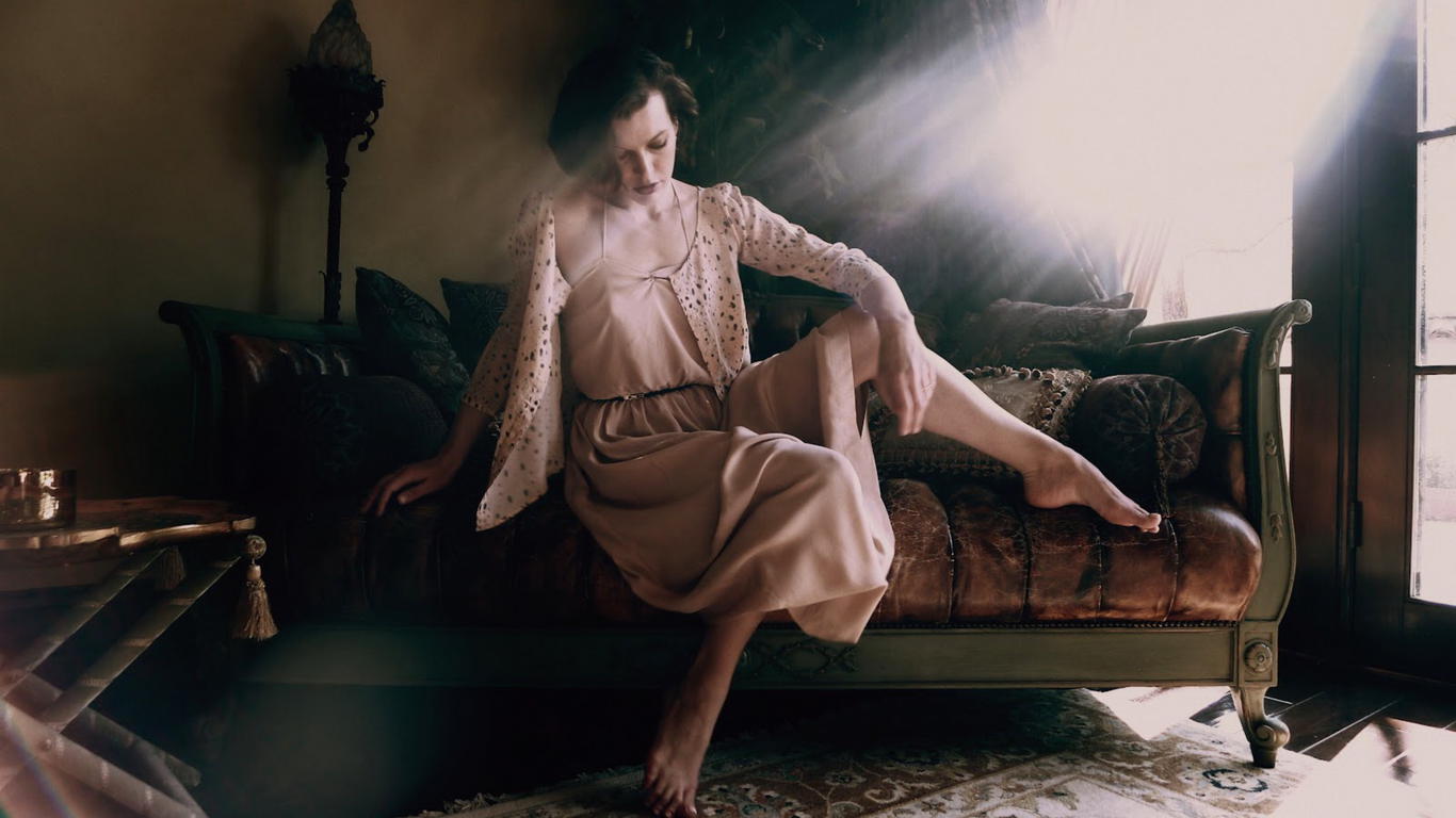 milla jovovich, actress, personality, hollywood, celebrity brunette, evening robe, eyes, hair, beautiful legs, room, sofa, beauty, graceful a foot, real celebs wall